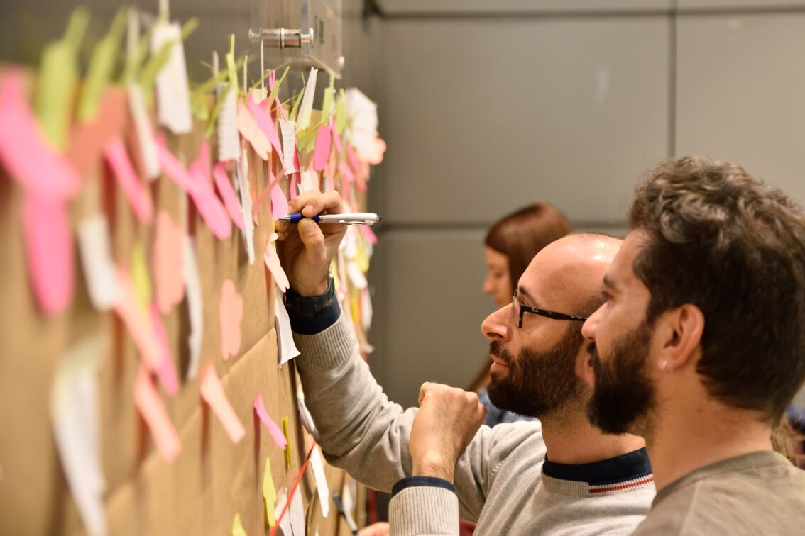 Persone che scrivono su un tabellone con post-it